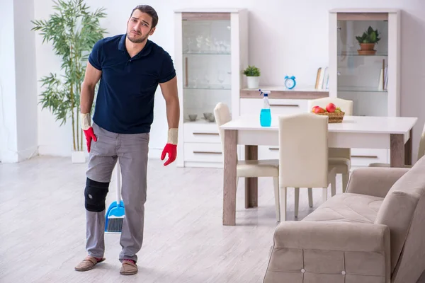 Young leg injured contractor cleaning the house — Stock Photo, Image