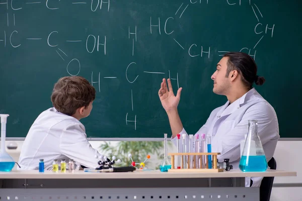 教室にいる若い化学教師と学童 — ストック写真