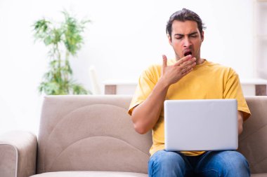 Evde bilgisayarı olan genç ve yakışıklı bir adam.