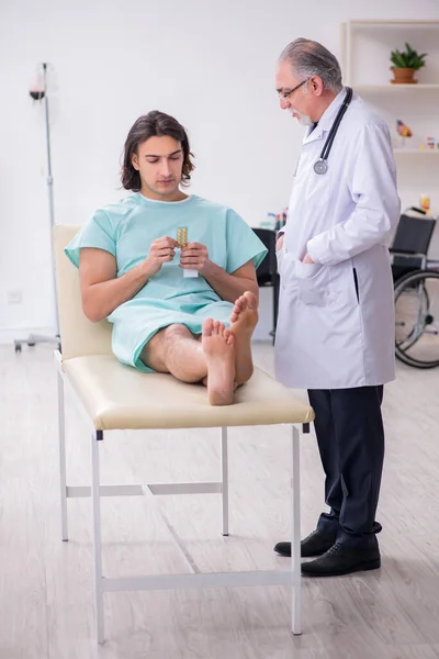 Jovem paciente do sexo masculino visitando médico experiente — Fotografia de Stock