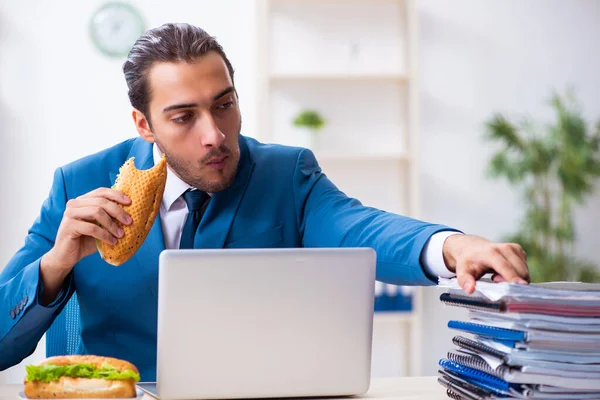 Joven empleado masculino desayunando en el lugar de trabajo — Foto de Stock