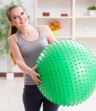 Spor salonunda denge topuyla egzersiz yapan genç bir kadın.