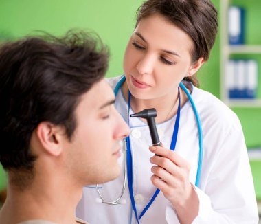 Tıbbi muayene sırasında kadın doktor hastaların kulaklarını kontrol ediyor.