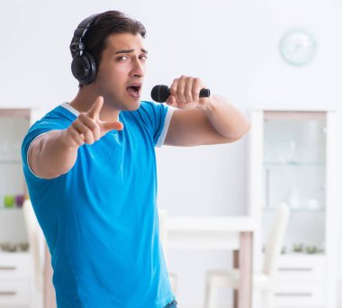 Genç yakışıklı adam evde karaoke yapıyor.