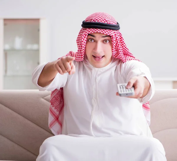 Joven árabe hombre viendo tv sentado en el sofá — Foto de Stock