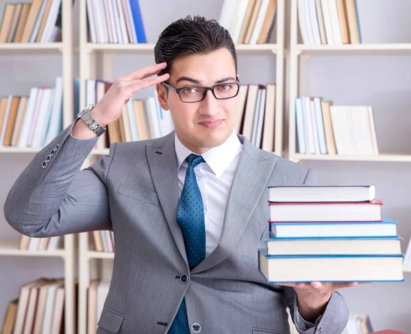 Student prawa gospodarczego z stosem książek pracujących w bibliotece — Zdjęcie stockowe