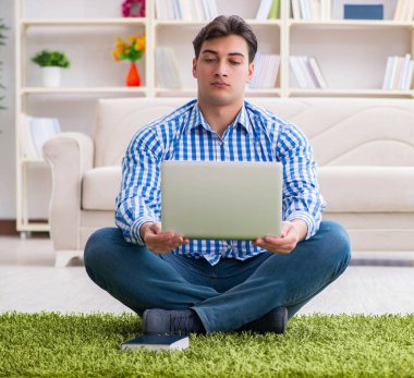 Genç yakışıklı adam evde yerde oturuyor.