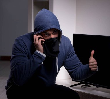 Hırsız, apartmandan televizyon çalıyor.