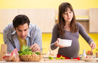 Erkek ve hamile kadın mutfakta salata hazırlıyorlar.