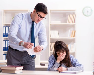 Erkek öğretim görevlisi bayan öğrenciye ders veriyor.