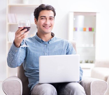 Genç adam evde şarap içiyor.