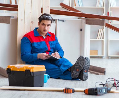 İnşaatta defter planlama yapan genç bir marangoz.