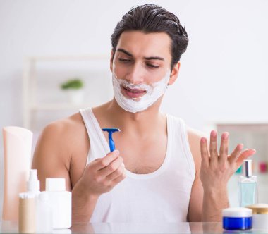 Genç yakışıklı adam sabah erkenden tıraş oluyor.