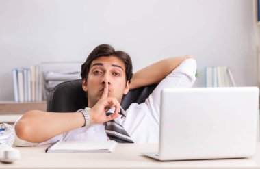 Genç yakışıklı işadamı ofiste çalışıyor.