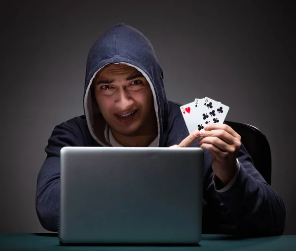 Young man wearing a hoodie sitting in front of a laptop computer — Stock Photo, Image