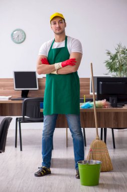 Genç müteahhit ofisi temizliyor.