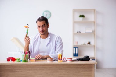Klinikte çalışan genç erkek dişçi.