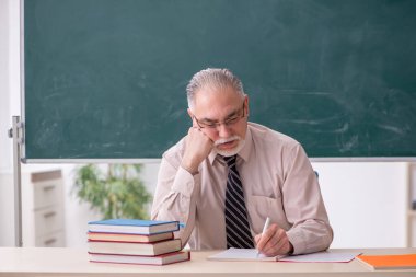 Sınıftaki yaşlı erkek öğretmen.