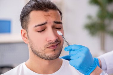 Genç adam deneyimli doktor dermatoloğu ziyaret ediyor.