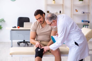 Deneyimli doktor travmatolog genç erkek hastayı muayene ediyor.