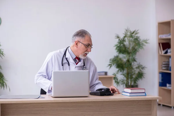 Klinikte çalışan yaşlı erkek doktor. — Stok fotoğraf