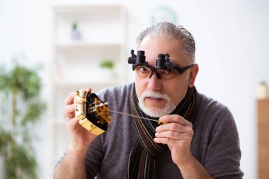 Atölyede çalışan yaşlı bir erkek saatçi.