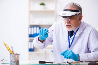 Kanıt için laboratuvarda çalışan yaşlı bir erkek kriminolog.