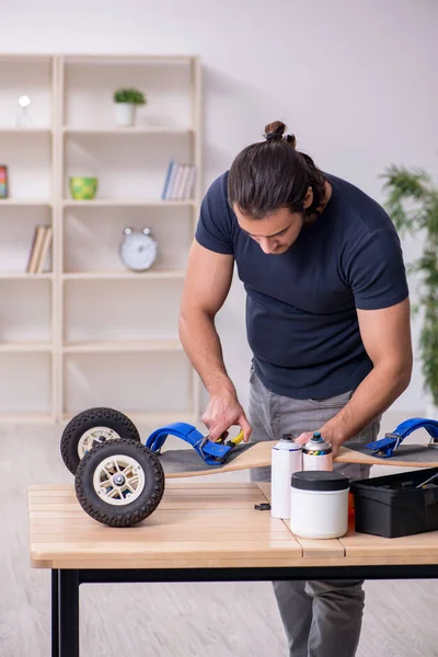 Jonge mannelijke reparateur die skateboard repareert — Stockfoto