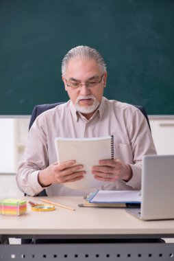 Sınıftaki yaşlı erkek öğretmen.