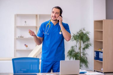 Klinikte çalışan genç erkek doktor.