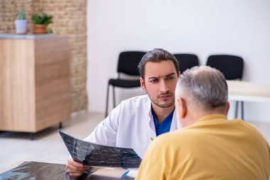 Yaşlı hasta, genç erkek doktor radyolojisti ziyaret ediyor.