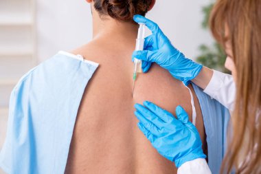 Genç sırtı yaralı bir adam, kadın doktor masörünü ziyaret ediyor.