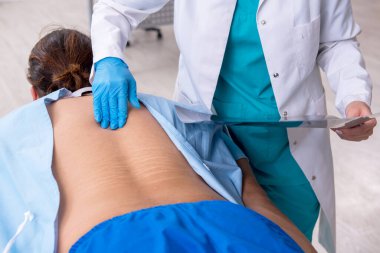 Genç sırtı yaralı bir adam, kadın doktor masörünü ziyaret ediyor.