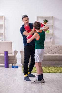 Baba ve oğul içeride spor yapıyor.