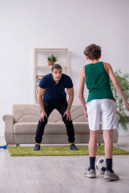 Baba ve oğul içeride spor yapıyor.