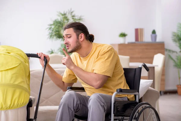 Jongeman aannemer in rolstoel op zoek naar pasgeborene — Stockfoto