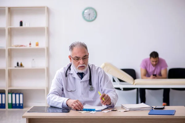 Ung manlig patient besöker gamla manliga läkare — Stockfoto