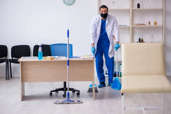 Joven contratista masculino desinfectando clínica en concepto pandémico —  Fotos de Stock