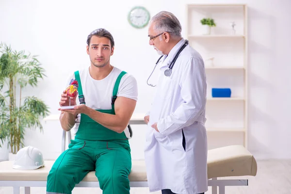 Young male contractor visiting old doctor