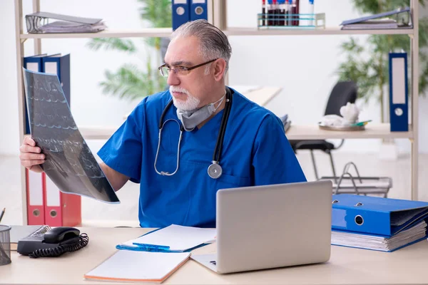 Old male doctor working in the clinic — Stock Photo, Image