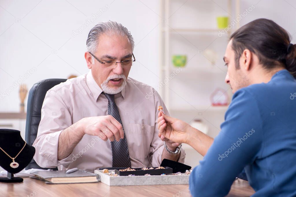 Young man visiting old male jeweler