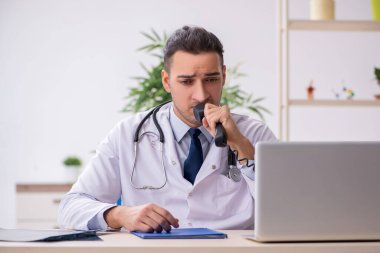 Klinikte çalışan genç erkek doktor.