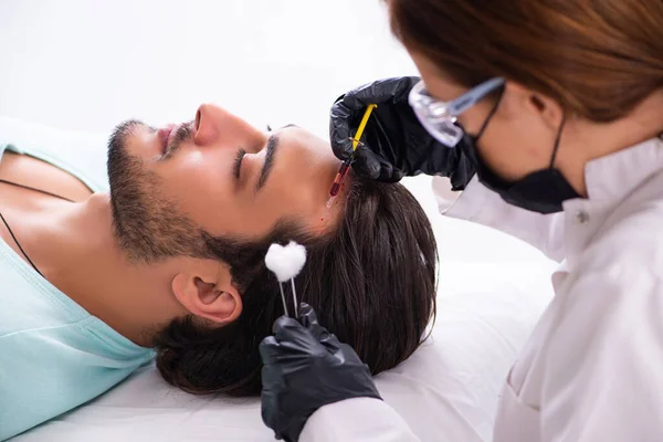 Young man visiting female beautician in hair transplantation con