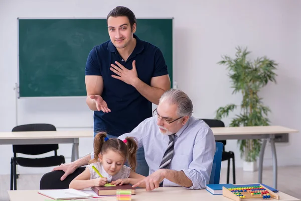 Jonge ouder, oude mannelijke leraar en klein meisje in de klas — Stockfoto