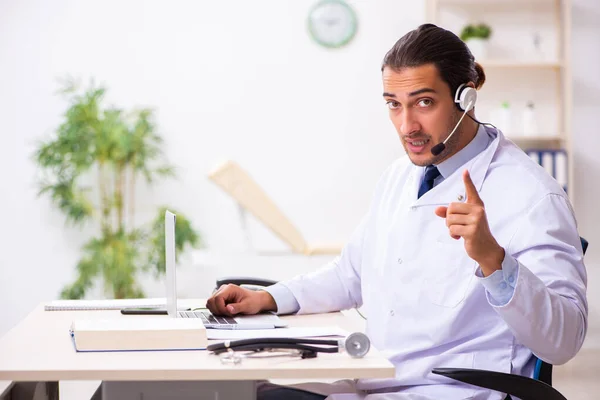 Junger Arzt hört Patient während telemedizinischer Sitzung zu — Stockfoto