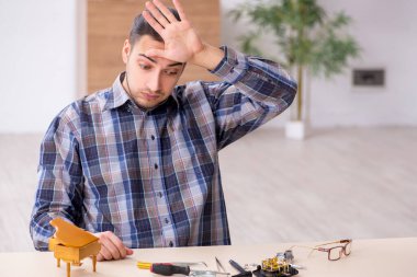 Genç erkek saatçi atölyede çalışıyor.