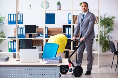 İş yerinde yeni doğan bebeğe bakan genç bir erkek işçi.