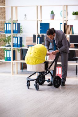 İş yerinde yeni doğan bebeğe bakan genç bir erkek işçi.