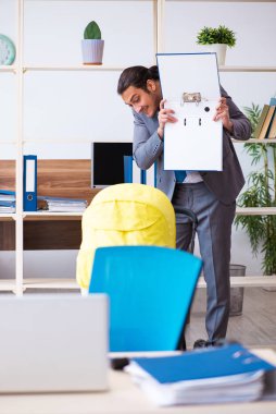 İş yerinde yeni doğan bebeğe bakan genç bir erkek işçi.