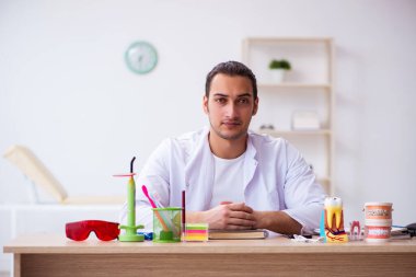 Klinikte çalışan genç erkek dişçi.